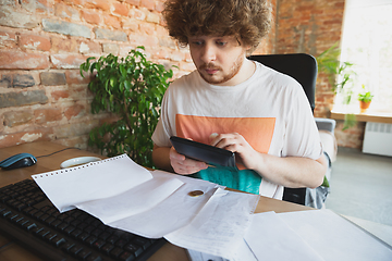 Image showing Caucasian upset and despair man doing financial and economical reports with income going down during coronavirus quarantine, problems