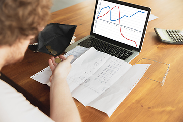 Image showing Close up caucasian upset and despair man doing financial and economical reports with income graphs going down during coronavirus quarantine, problems, empty wallet