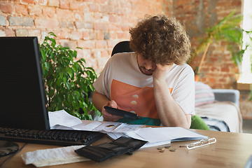 Image showing Caucasian upset and despair man doing financial and economical reports with income going down during coronavirus quarantine, problems