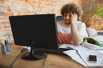 Image showing Caucasian upset and despair man watching financial and economical graphs going down during coronavirus quarantine, problems