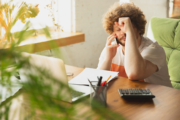 Image showing Caucasian upset and despair man watching financial and economical reports with income graphs going down during coronavirus quarantine. Problems, empty wallet