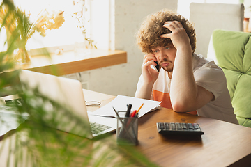 Image showing Caucasian upset and despair man watching financial and economical reports with income graphs going down during coronavirus quarantine. Problems, empty wallet