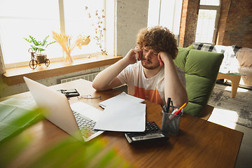 Image showing Caucasian upset and despair man watching financial and economical reports with income graphs going down during coronavirus quarantine. Problems, empty wallet