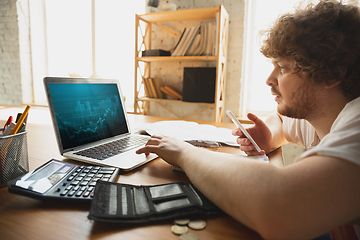 Image showing Caucasian upset and despair man watching financial and economical graphs going down during coronavirus quarantine, problems