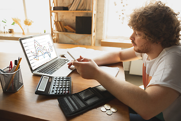 Image showing Caucasian upset and despair man watching financial and economical graphs going down during coronavirus quarantine, problems