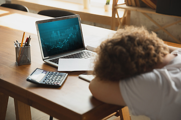 Image showing Caucasian upset and despair man watching financial and economical graphs going down during coronavirus quarantine, problems