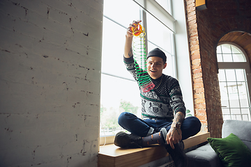 Image showing Portrait of millenial boy using retro toys, meeting things from the past and having fun, exploring rainbow spring toy