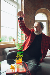 Image showing Portrait of senior man with retro toys, meeting things from the past and having fun, exploring the lifestyle of the nineties, playing with rainbow spring toy