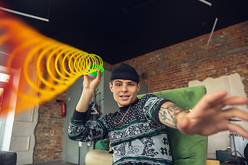 Image showing Portrait of millenial boy using retro toys, meeting things from the past and having fun, exploring rainbow spring toy