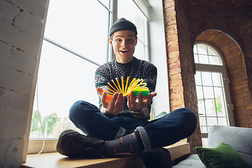 Image showing Portrait of millenial boy using retro toys, meeting things from the past and having fun, exploring rainbow spring toy