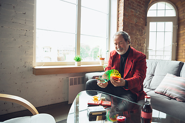 Image showing Portrait of senior man with retro toys, meeting things from the past and having fun, exploring the lifestyle of the nineties, playing with rainbow spring toy