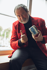 Image showing Portrait of senior man with retro toys, meeting things from the past and having fun, exploring the lifestyle of the nineties, using cassette player