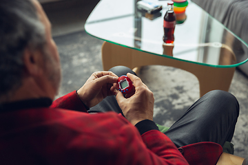 Image showing Close up of senior man with retro toys, meeting things from the past and having fun, exploring the lifestyle of the nineties, playing with tamagotchi