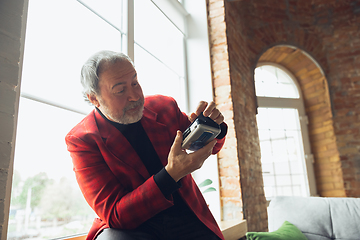 Image showing Portrait of senior man with retro toys, meeting things from the past and having fun, exploring the lifestyle of the nineties, using cassette player