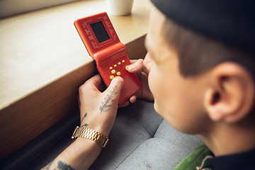 Image showing Close up of millenial boy using retro toys, meeting things from the past and having fun, exploring tetris game