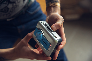 Image showing Close up of millenial boy using retro toys, meeting things from the past and having fun, exploring music cassette player