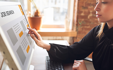 Image showing Female hand touching screen while looking for a job during worldwide crisis of coronavirus pandemic. Find a job online. Business, internet and networking concept.