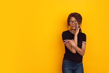 Image showing African-american beautiful young woman\'s portrait on yellow studio background, emotional and expressive. Copyspace for ad.