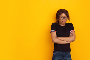 Image showing African-american beautiful young woman\'s portrait on yellow studio background, emotional and expressive. Copyspace for ad.