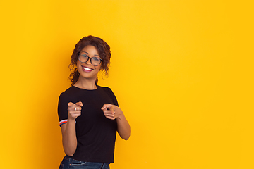 Image showing African-american beautiful young woman\'s portrait on yellow studio background, emotional and expressive. Copyspace for ad.