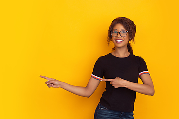 Image showing African-american beautiful young woman\'s portrait on yellow studio background, emotional and expressive. Copyspace for ad.