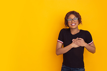 Image showing African-american beautiful young woman\'s portrait on yellow studio background, emotional and expressive. Copyspace for ad.