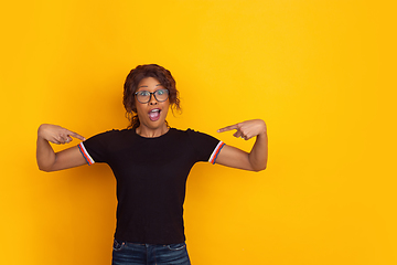 Image showing African-american beautiful young woman\'s portrait on yellow studio background, emotional and expressive. Copyspace for ad.