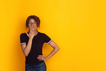 Image showing African-american beautiful young woman\'s portrait on yellow studio background, emotional and expressive. Copyspace for ad.