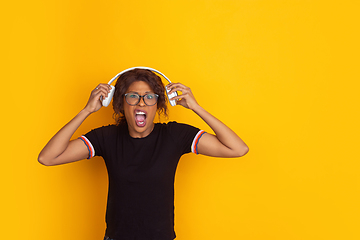 Image showing African-american beautiful young woman\'s portrait on yellow studio background, emotional and expressive. Copyspace for ad.