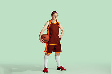 Image showing Young caucasian female basketball player against mint colored studio background