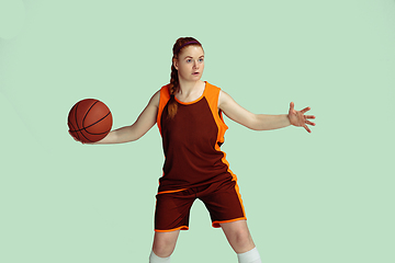 Image showing Young caucasian female basketball player against mint colored studio background