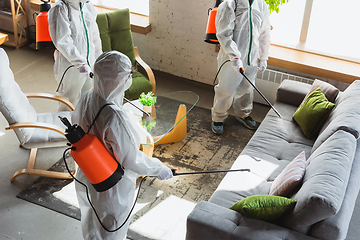 Image showing Coronavirus Pandemic. A disinfectors in a protective suit and mask sprays disinfectants in the house or office