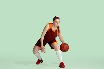 Image showing Young caucasian female basketball player against mint colored studio background