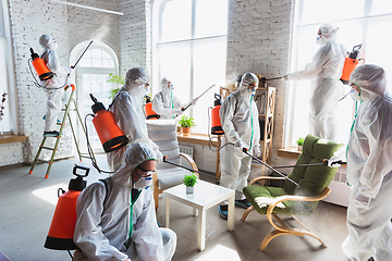 Image showing Coronavirus Pandemic. A disinfectors in a protective suit and mask sprays disinfectants in the house or office