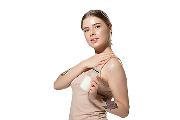 Image showing Beautiful young woman massaging her skin with moisturizer over white background. Cosmetics and makeup, natural and eco treatment, skin care.