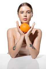 Image showing Youth secrets. Beautiful young woman with orange over white background. Cosmetics and makeup, natural and eco treatment, skin care.