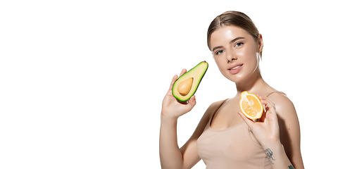 Image showing Vitamins. Beautiful young woman with fresh avocado and orange pieces over white background. Cosmetics and makeup, natural and eco treatment, skin care. Flyer with copyspace.