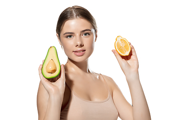 Image showing Vitamins. Beautiful young woman with fresh avocado and orange pieces over white background. Cosmetics and makeup, natural and eco treatment, skin care.