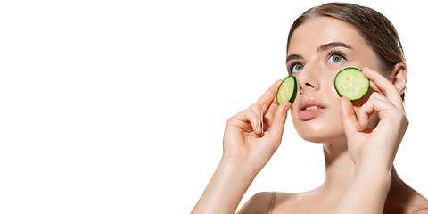 Image showing Nature way. Beautiful young woman with fresh cucumber on her face over white background. Cosmetics and makeup, natural and eco treatment, skin care. Flyer.