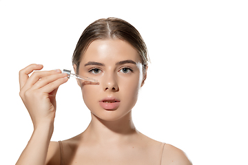 Image showing Skin nutrition. Beautiful young woman with essential oil pouring over white background. Cosmetics and makeup, natural and eco treatment, skin care.