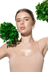 Image showing Vitamins. Close up of beautiful young woman with green leaves on her face over white background. Cosmetics and makeup, natural and eco treatment, skin care