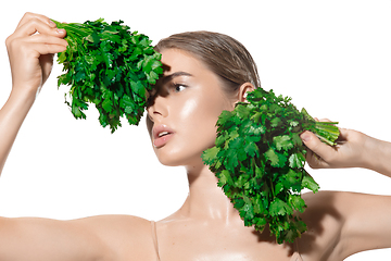 Image showing Vitamins. Close up of beautiful young woman with green leaves on her face over white background. Cosmetics and makeup, natural and eco treatment, skin care