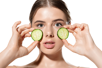 Image showing Freshness. Beautiful young woman with fresh cucumber on her face over white background. Cosmetics and makeup, natural and eco treatment, skin care.