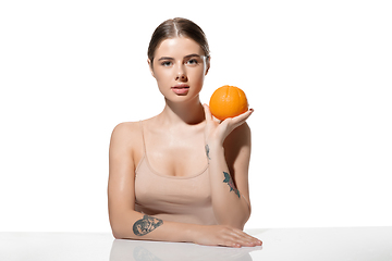 Image showing Youth secrets. Beautiful young woman with orange over white background. Cosmetics and makeup, natural and eco treatment, skin care.