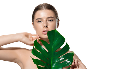 Image showing Touch. Portrait of beautiful young woman with green leaf on her face over white background. Cosmetics and makeup, natural and eco treatment, skin care. Flyer with copyspace.