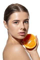 Image showing Freshness. Beautiful young woman with half of orange over white background. Cosmetics and makeup, natural and eco treatment, skin care.