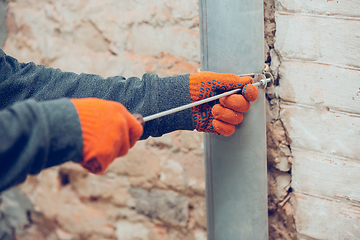 Image showing Close up of hands of repairman, professional builder working indoors, installs sewer, duct