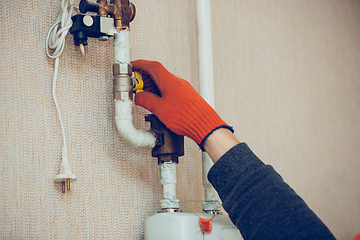 Image showing Male hand closes the wick of a gas bottle, heater, shuts off the flow