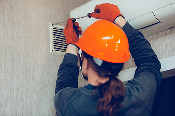 Image showing Industrial builder, handyman installing ventilation or air conditioning filter holder in wall