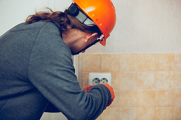 Image showing Electrician repair a wall socket. Closeup of man repairing an electrical outlet. Hazardous concept, high voltage, risk, wiring replacement, technician\'s occupation